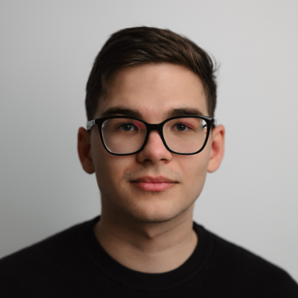 Portrait of a young man with dark hair and black glasses.